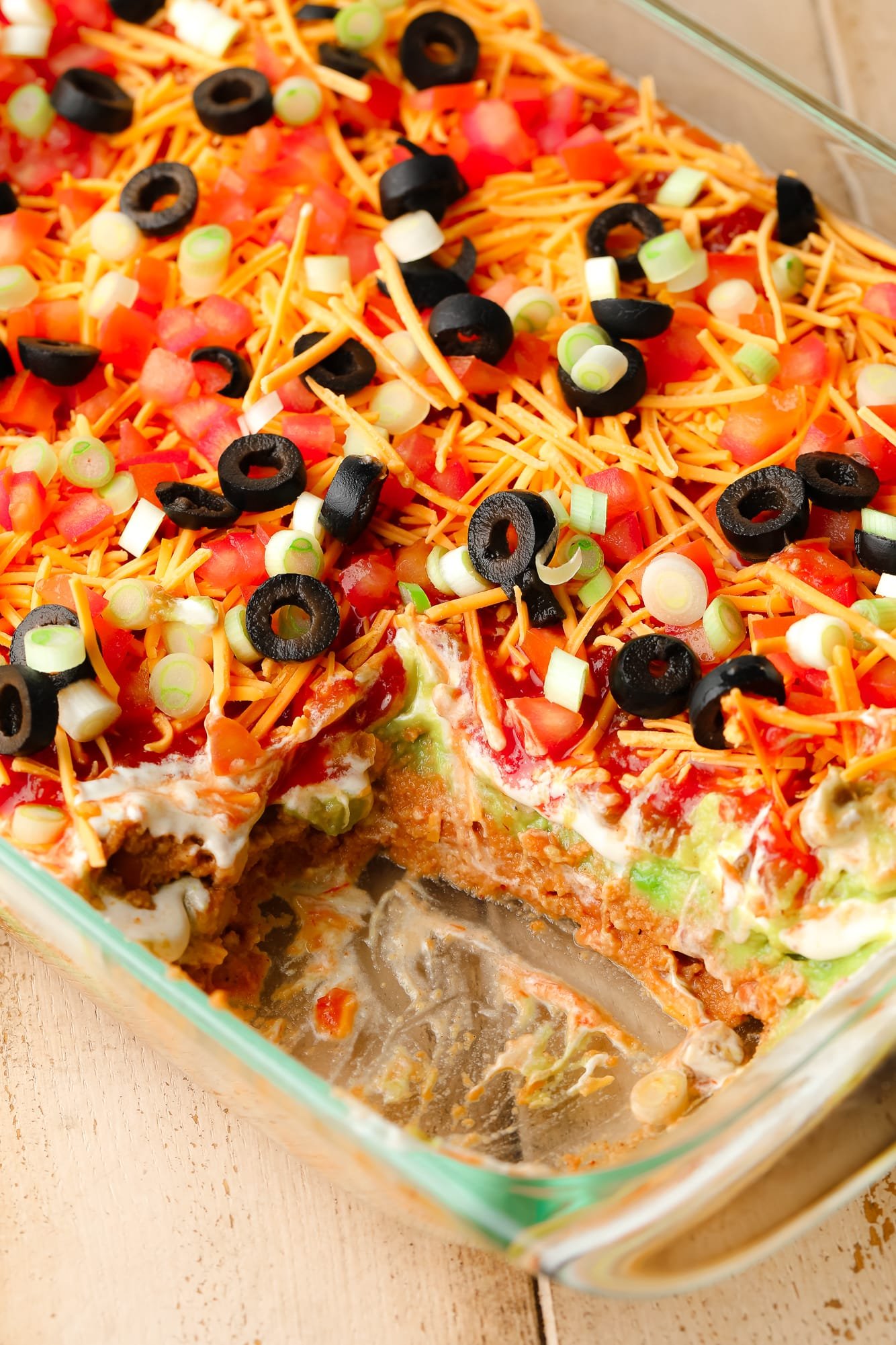 close up on a vegan 7 layer dip in a glass dish.