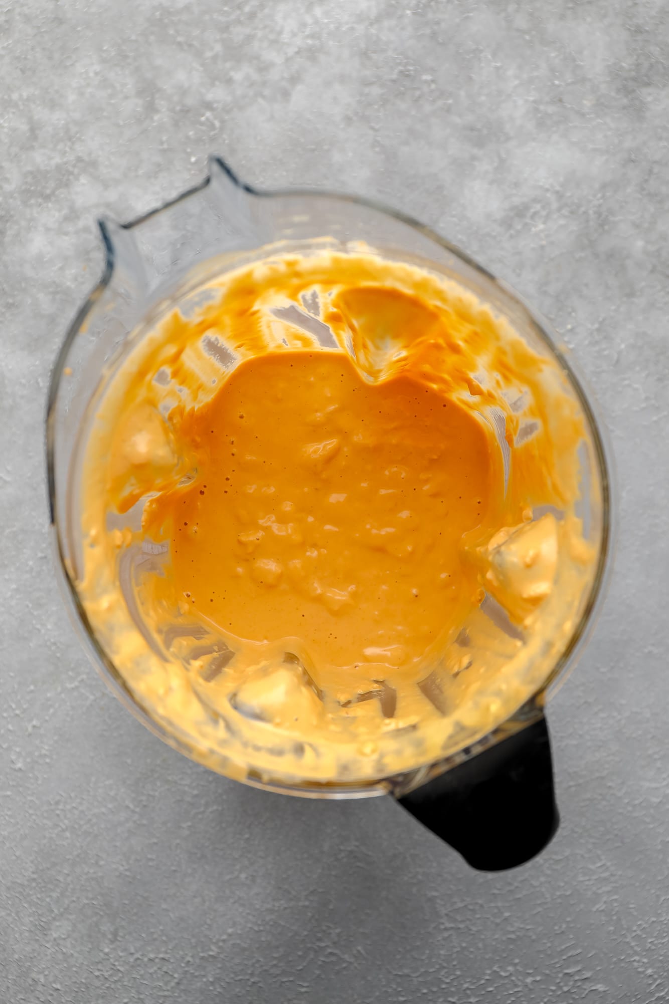 creamy orange vegan buffalo cheese sauce in a blender.