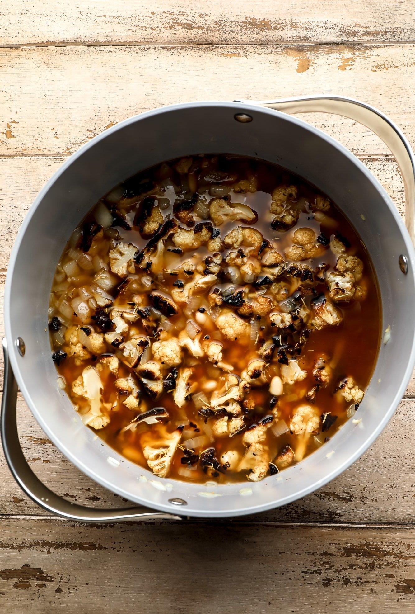 the ingredients for roasted cauliflower soup in a large grey pot.