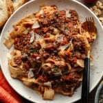 square image of wide noodles with chunky lentil sauce in a bowl