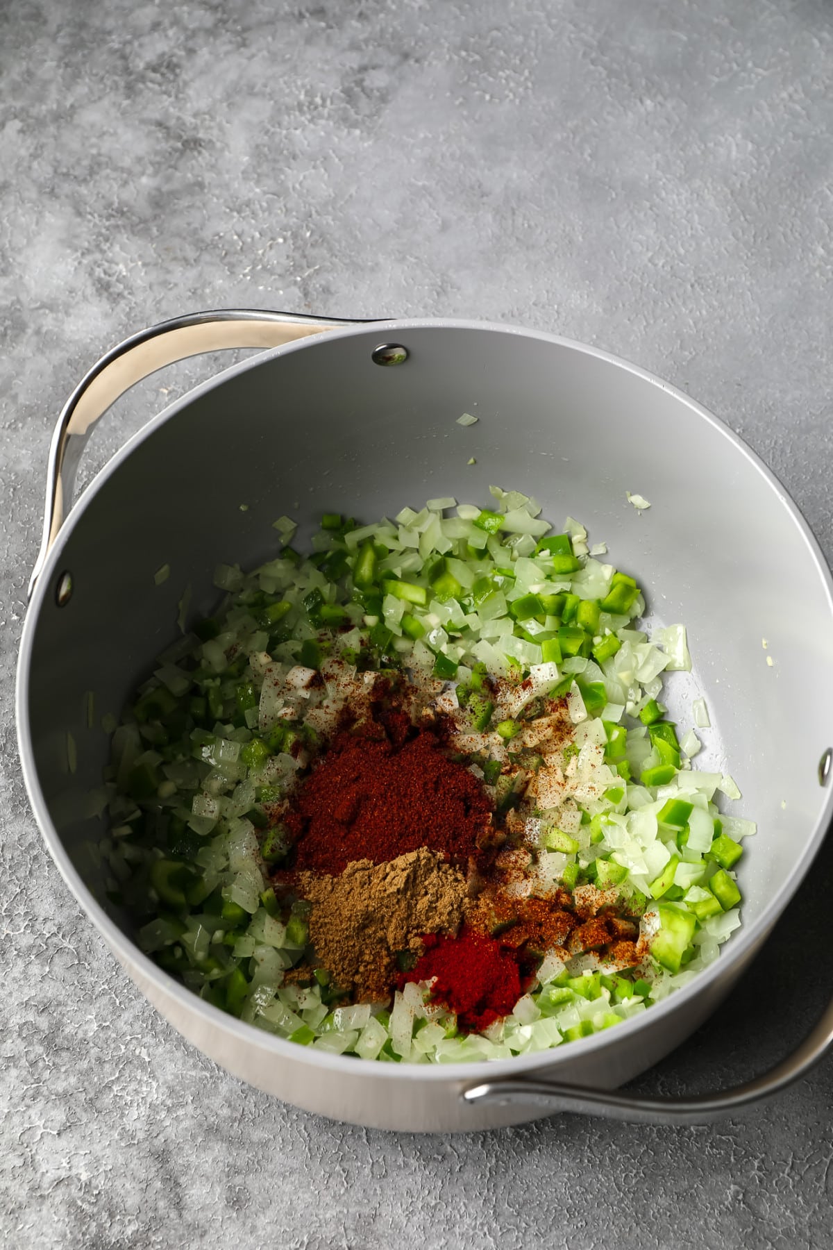 light grey pot of sauteed peppers and onions with spices added on top