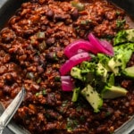 bowl of beans and peppers in broth with pickled onions and avocado