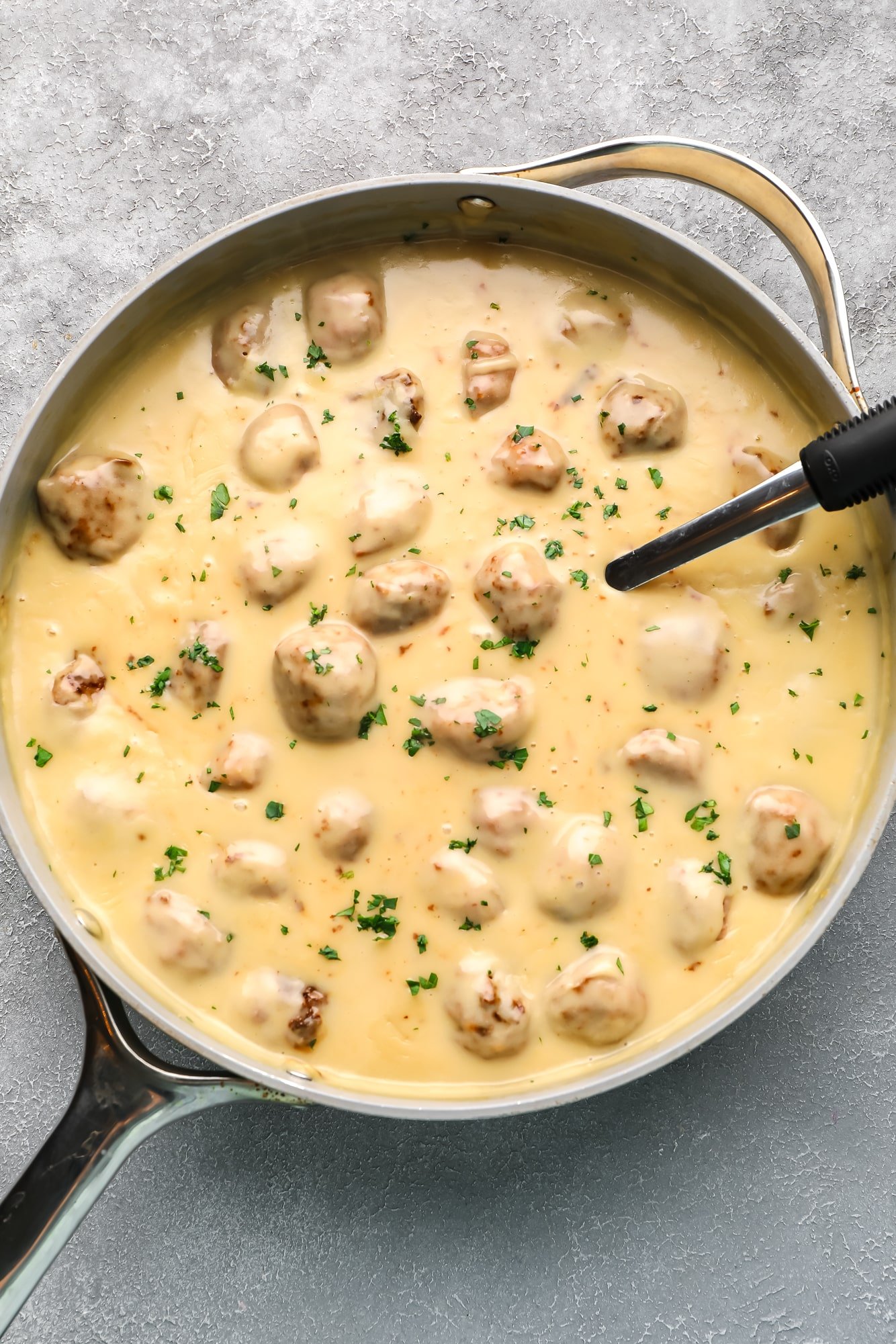 vegan Swedish meatballs in a creamy sauce in a large grey skillet.
