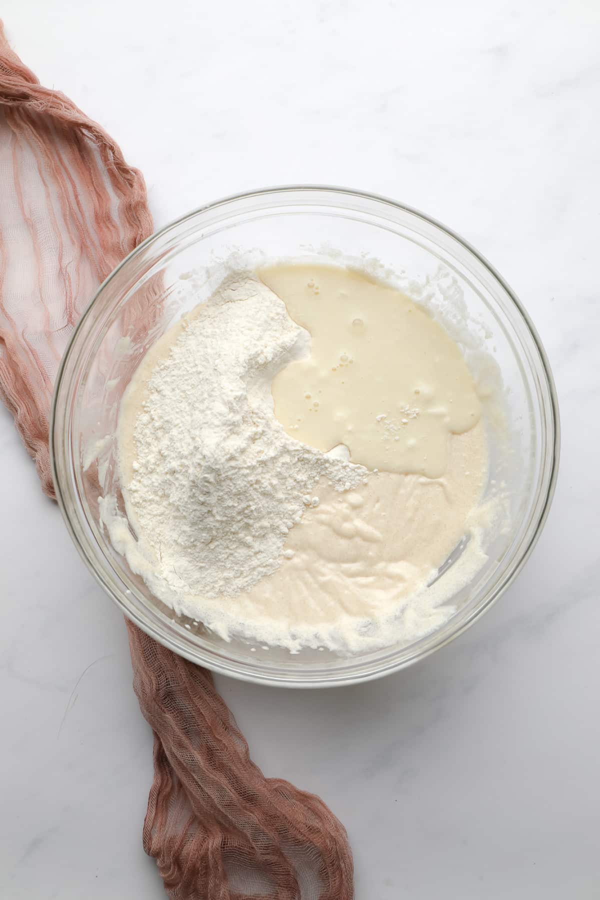 glass bowl with flour and milk being added to wet mixture