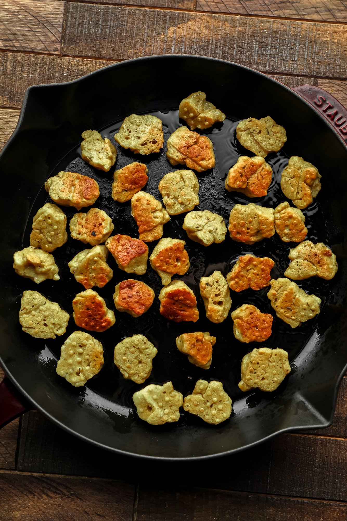 frying seitan nuggets in a large black skillet.