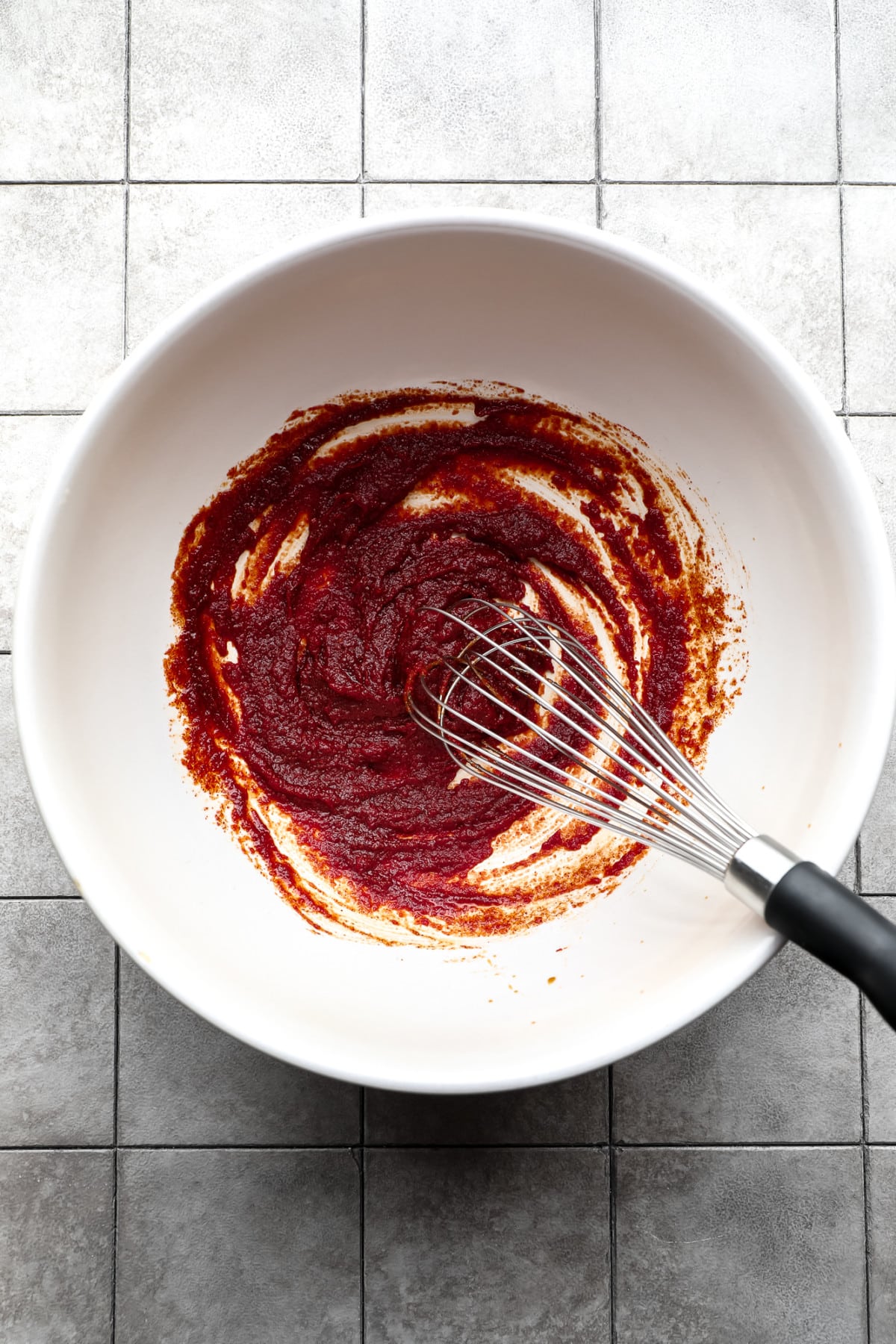 thick dark red sauce being whisked in a large bowl
