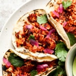 close up of tofu tacos on a plate with cilantro and pickled red onion