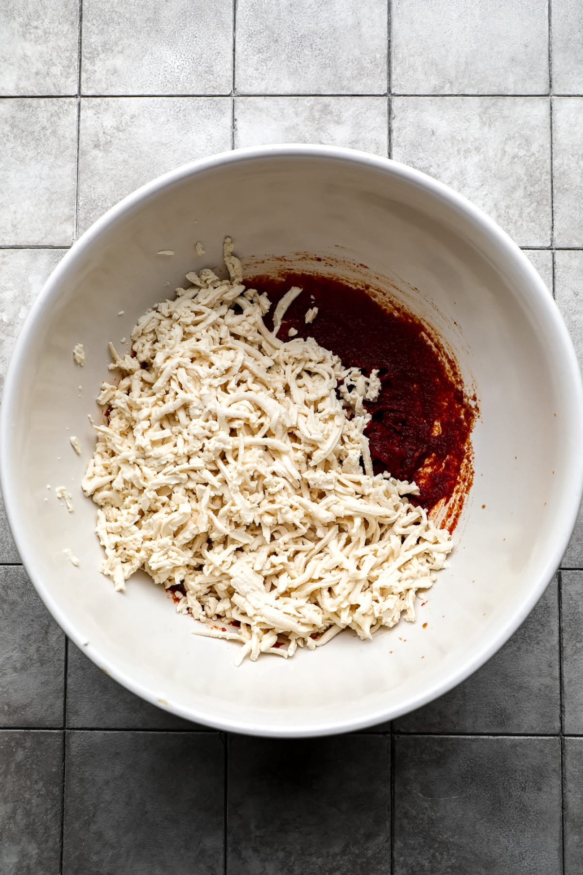 shredded tofu in a bowl with a reddish sauce, not mixed