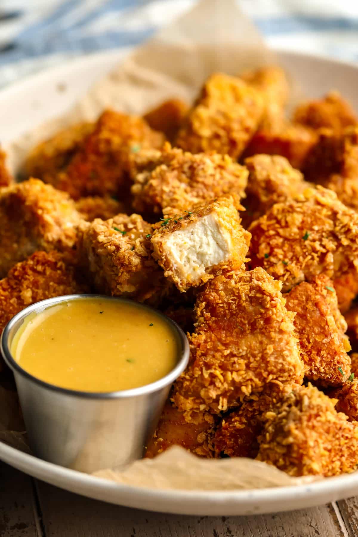 lots of vegan chicken nuggets in a bowl with one showing the inside