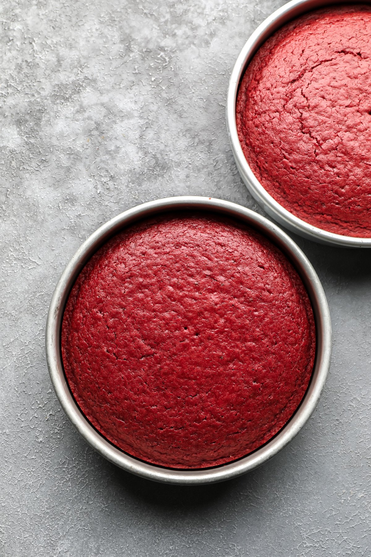 cooked vegan red velvet cakes in round pans on grey background