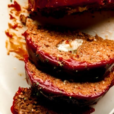 close up on slices of vegan Impossible meatloaf stuffed with vegan cheese and topped with a sticky red glaze.