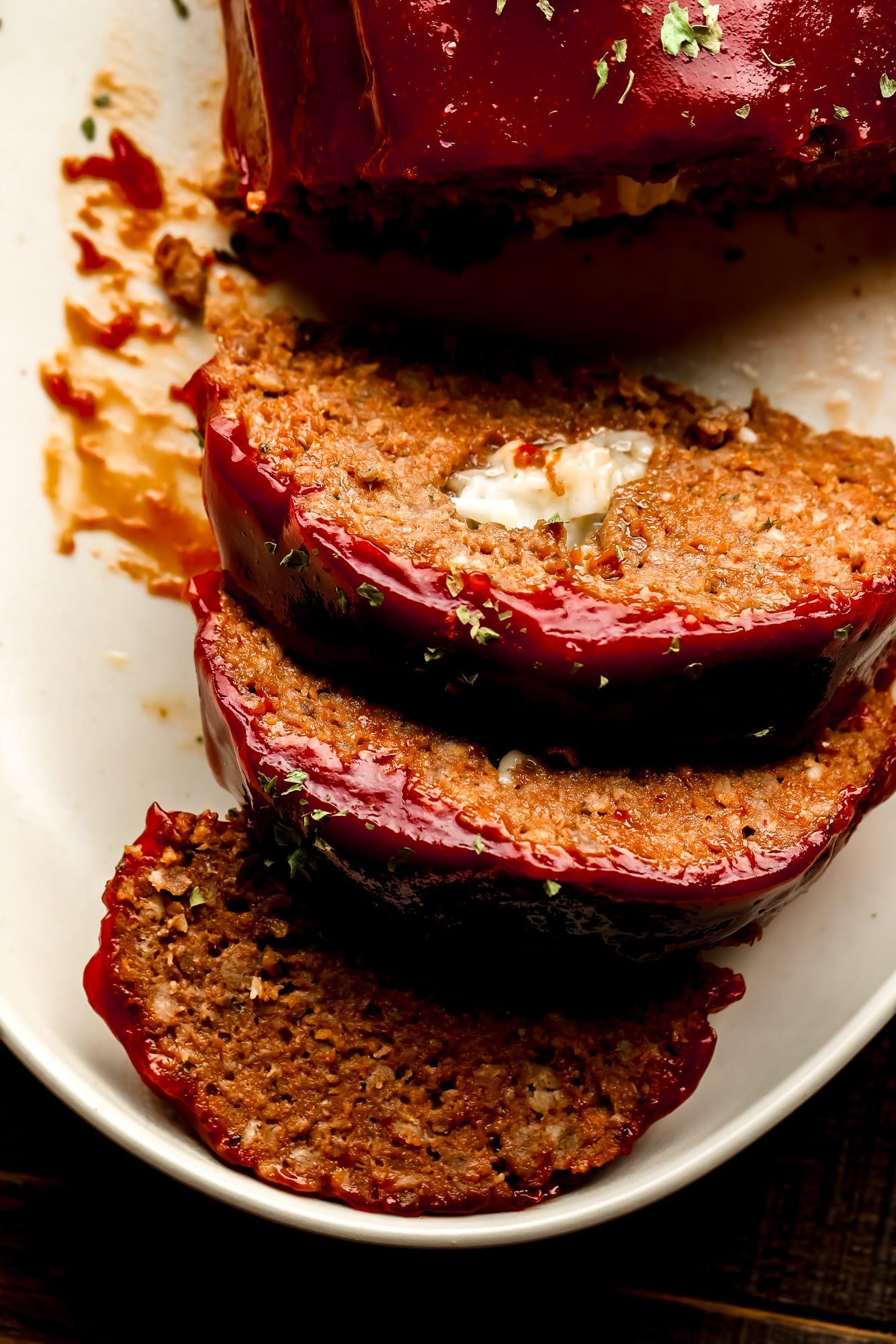 close up on slices of vegan Impossible meatloaf stuffed with vegan cheese and topped with a sticky red glaze.