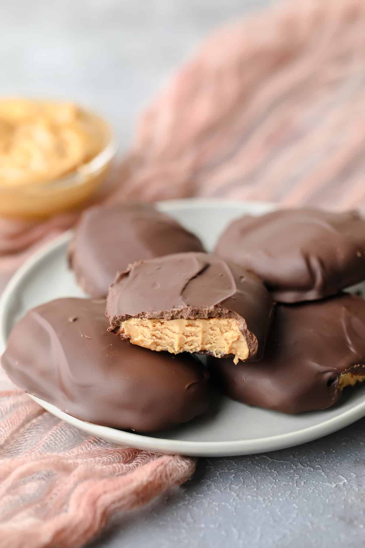 a bite taken out of a vegan peanut butter egg on grey plate with more underneath it