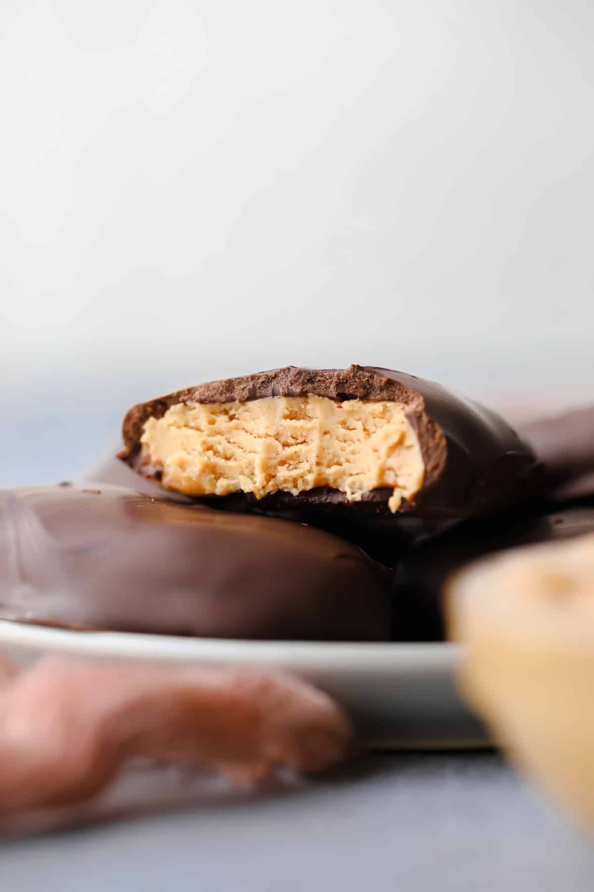 close up of peanut butter egg with a bite taken, showing peanut butter inside, on grey background