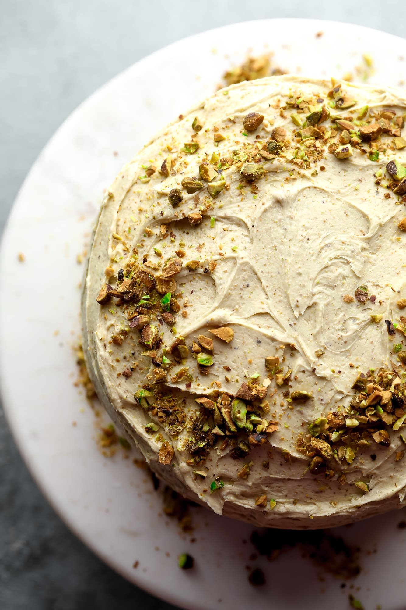 vegan pistachio cake decorated with pistachio frosting and crushed pistachios.