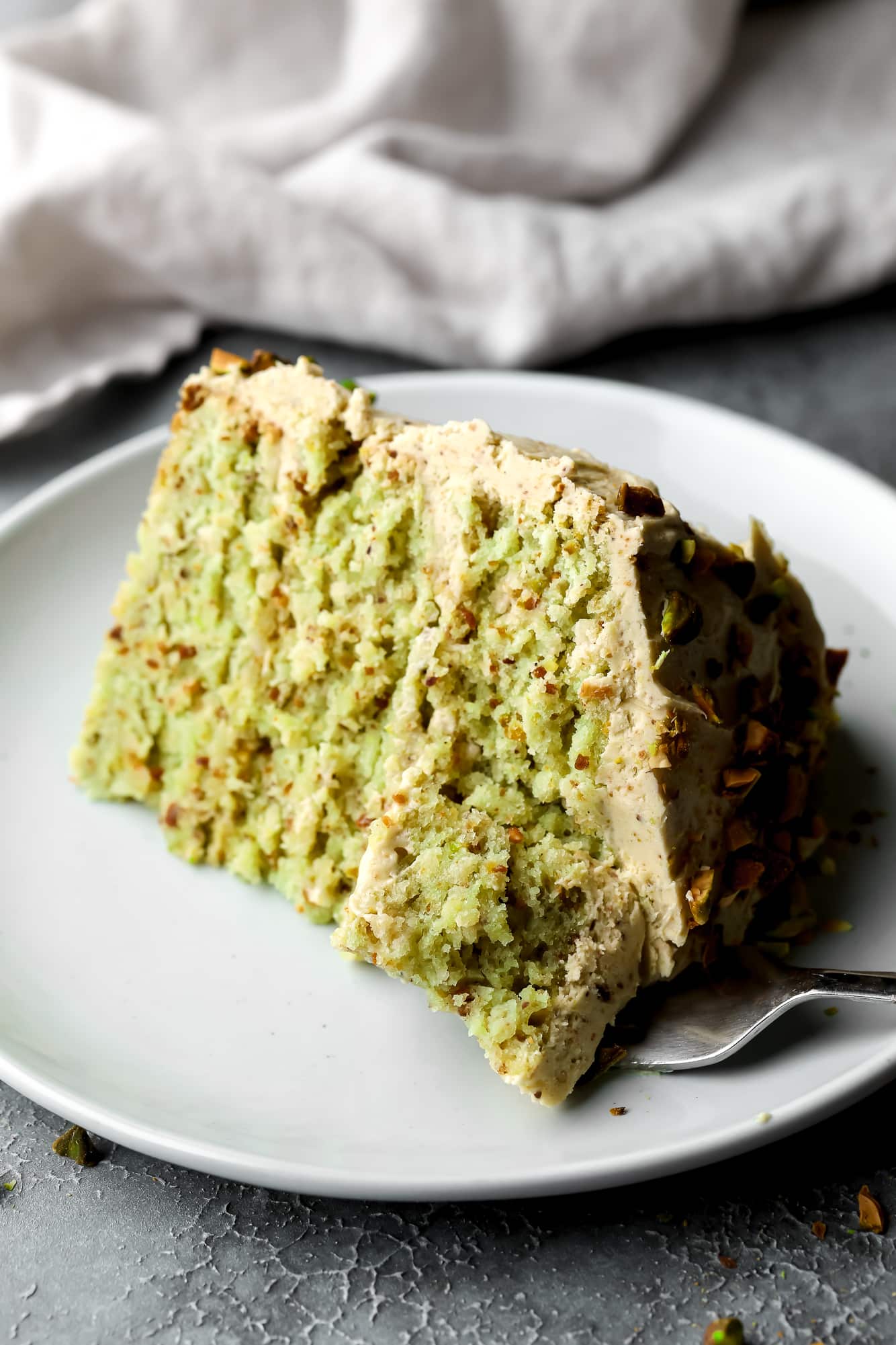 a slice of vegan pistachio cake on a white plate.