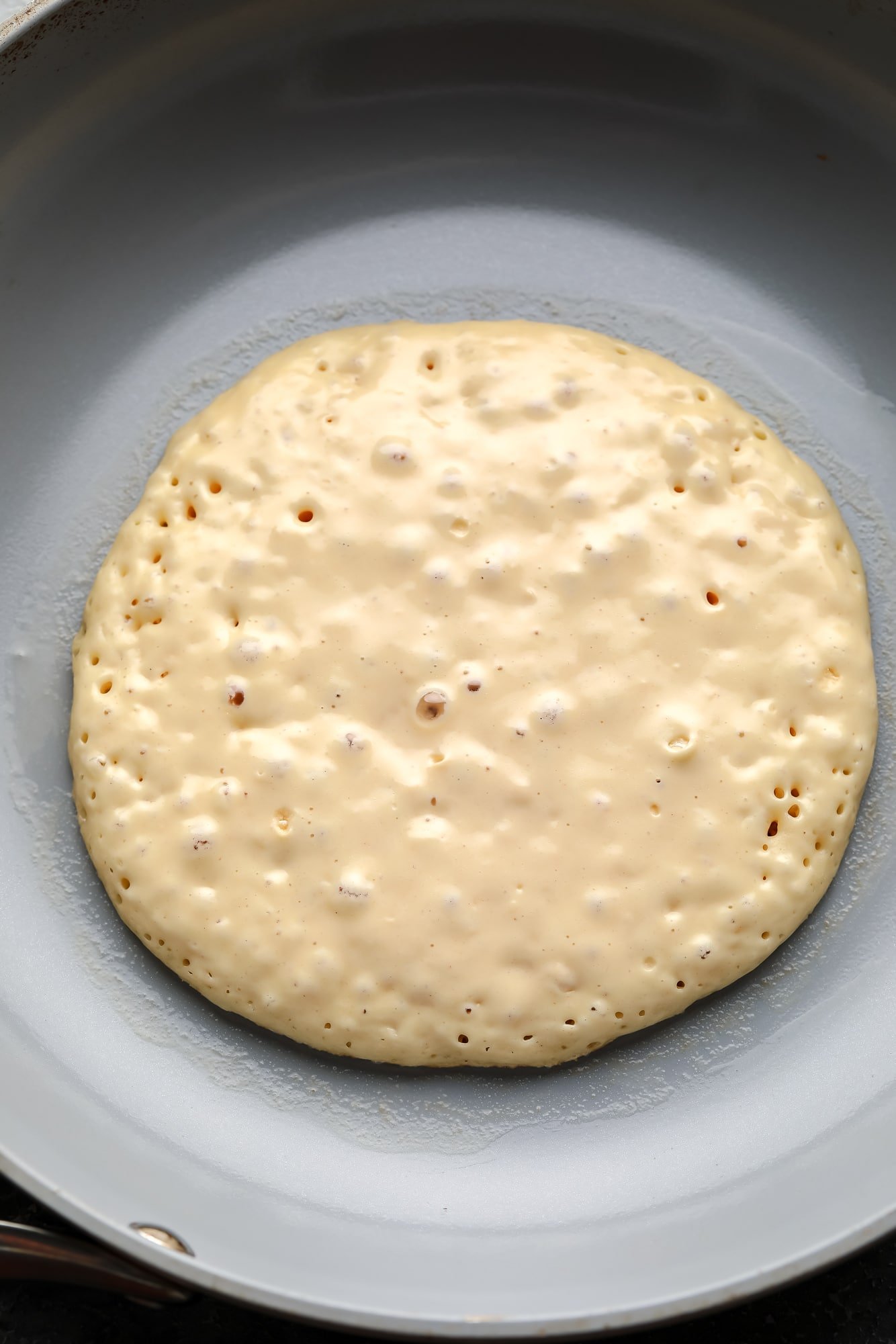 cooking a vegan pancake in a grey skillet.