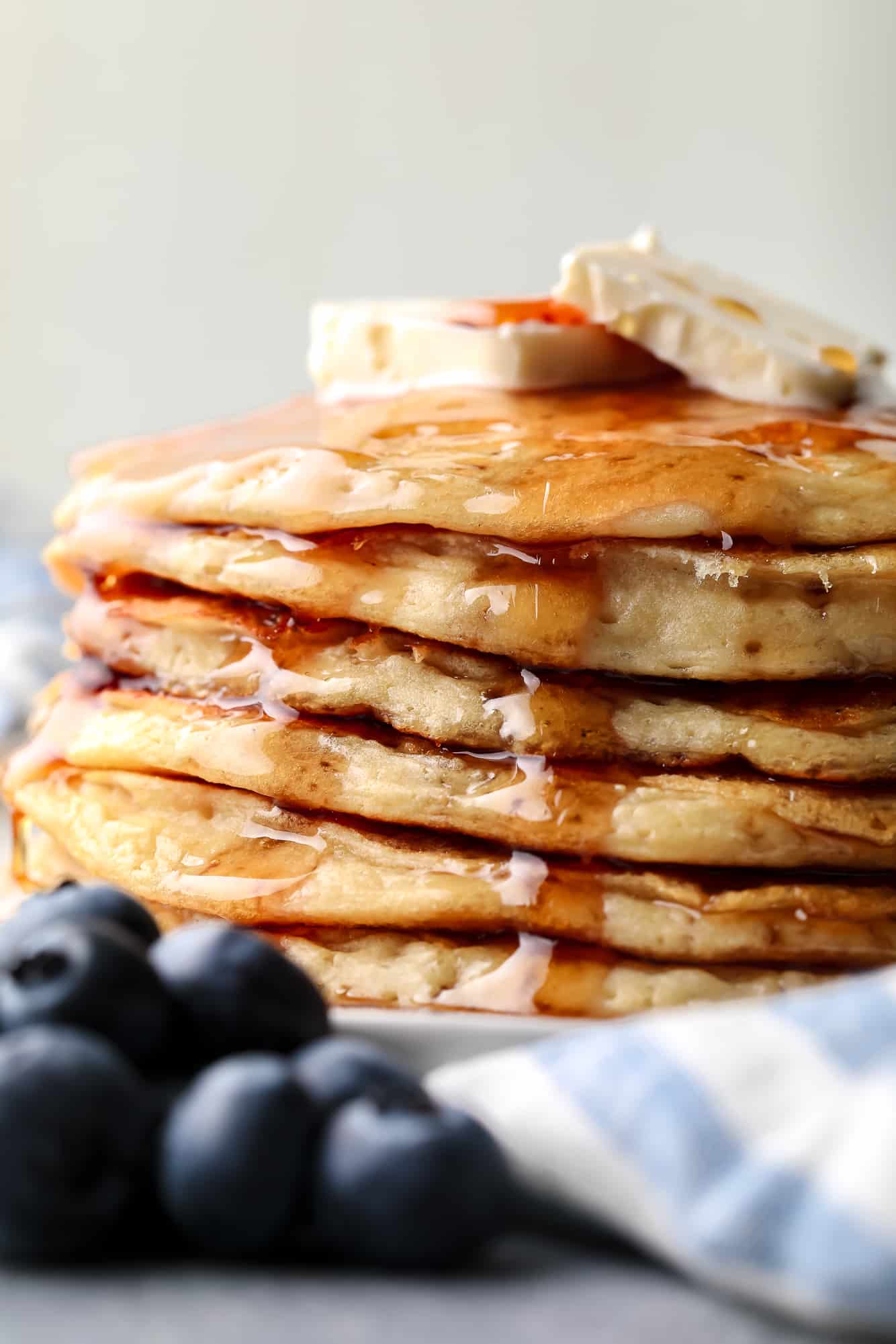 a stack of vegan protein pancakes topped with maple syrup and banana slices.