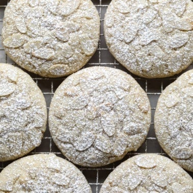 close up on Vegan Almond Croissant Cookies topped with sliced almonds and dusted with powdered sugar.