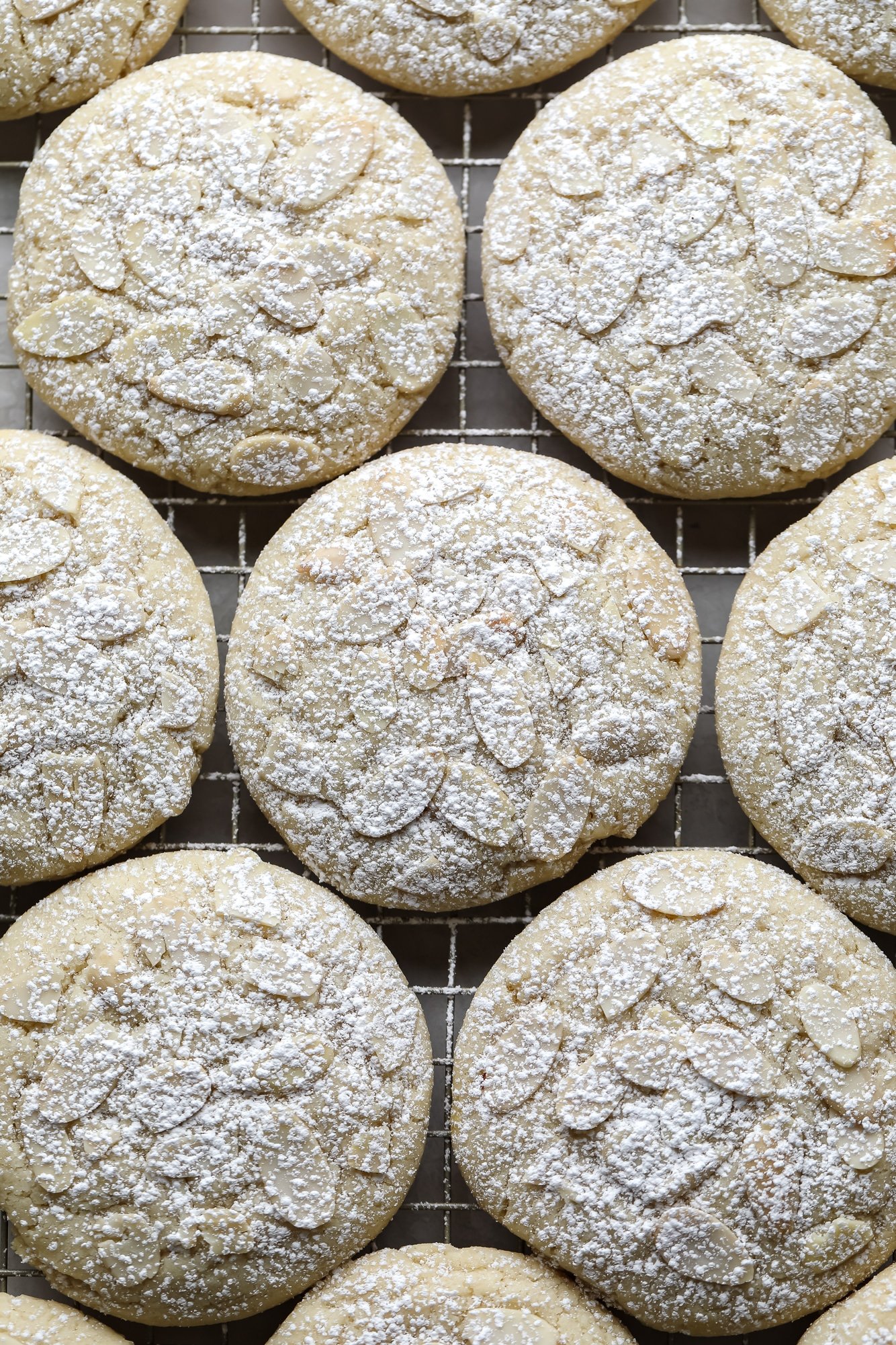 close up on Vegan Almond Croissant Cookies topped with sliced almonds and dusted with powdered sugar.