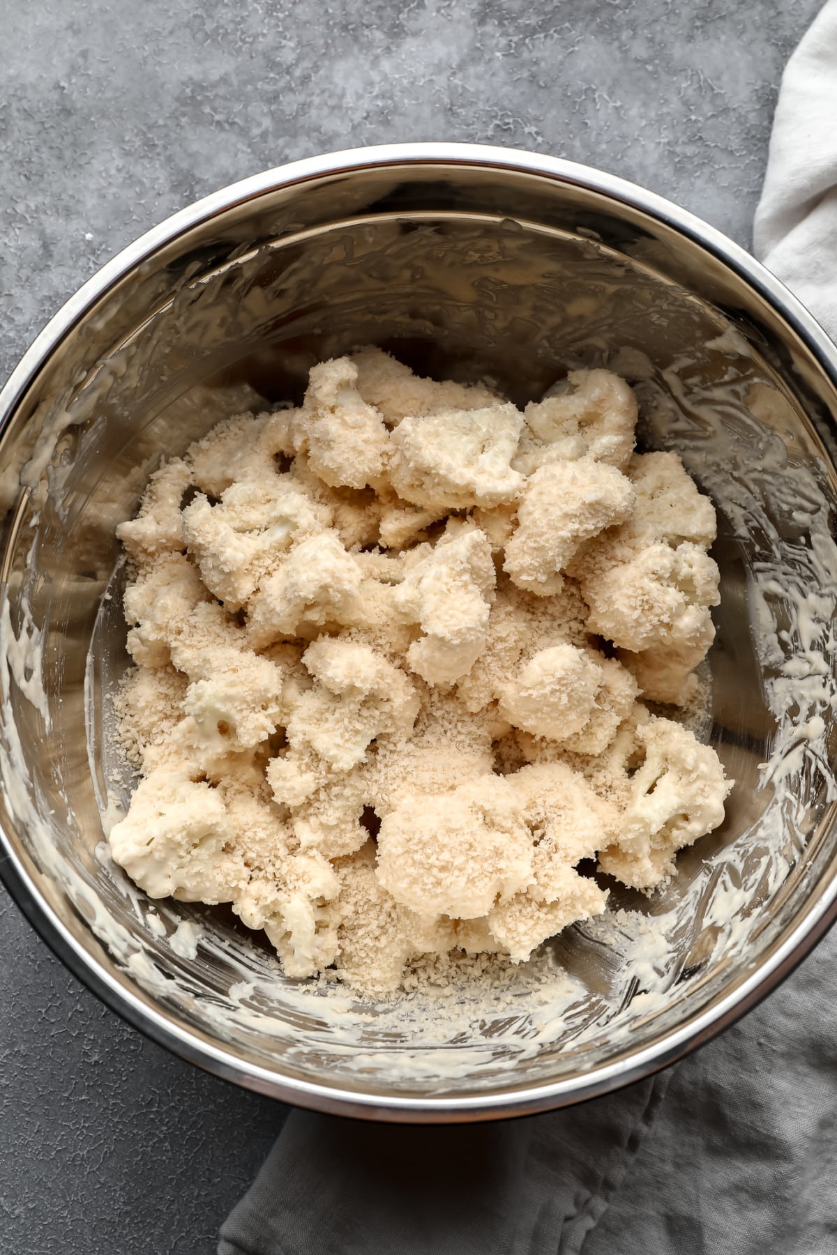 cauliflower florets mixed with flour mixture and breadcrumbs in silver bowl