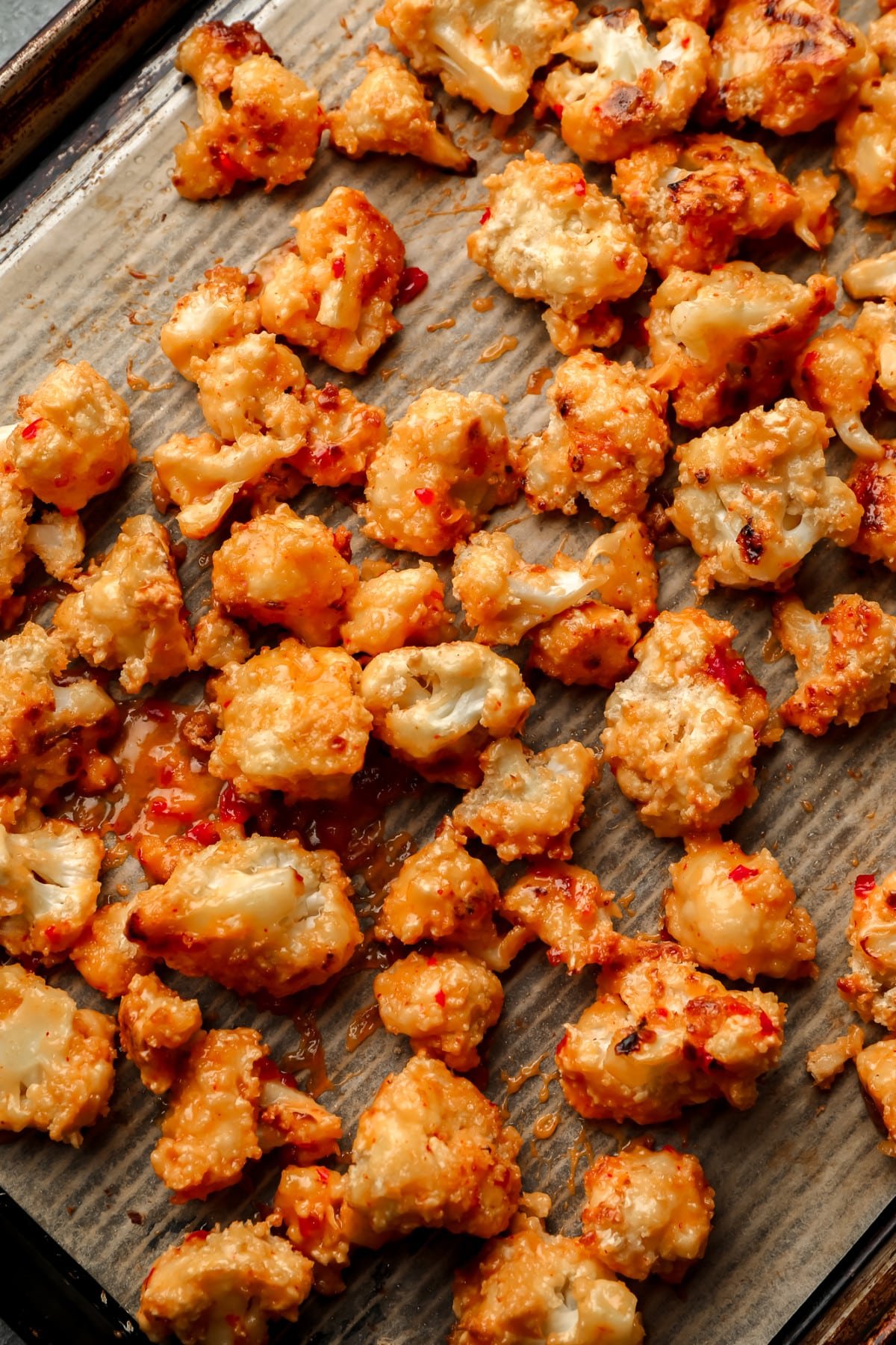 baked bang bang cauliflower on parchment lined baking sheet