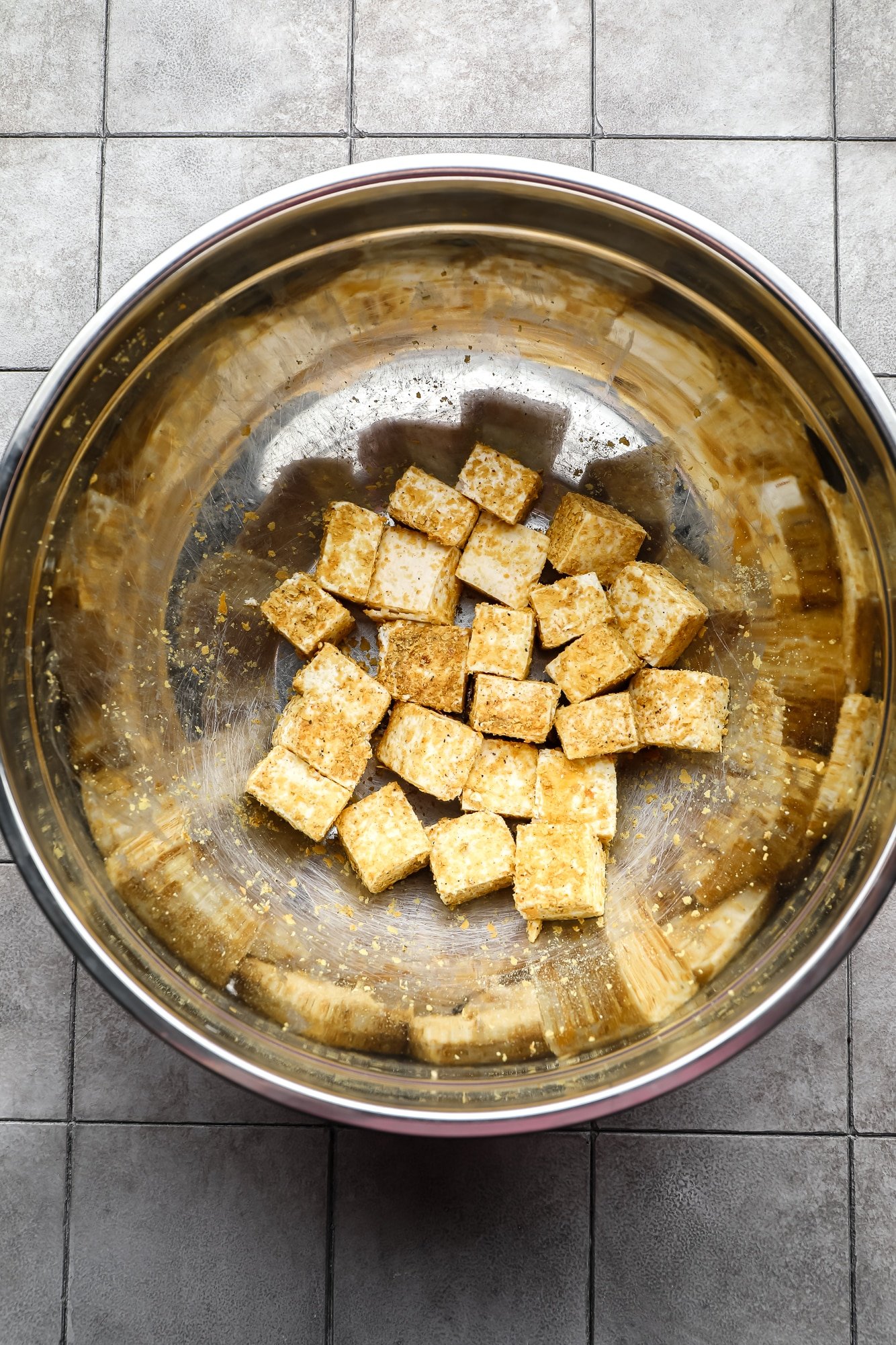 seasoned tofu cubes in a large metal bowl.