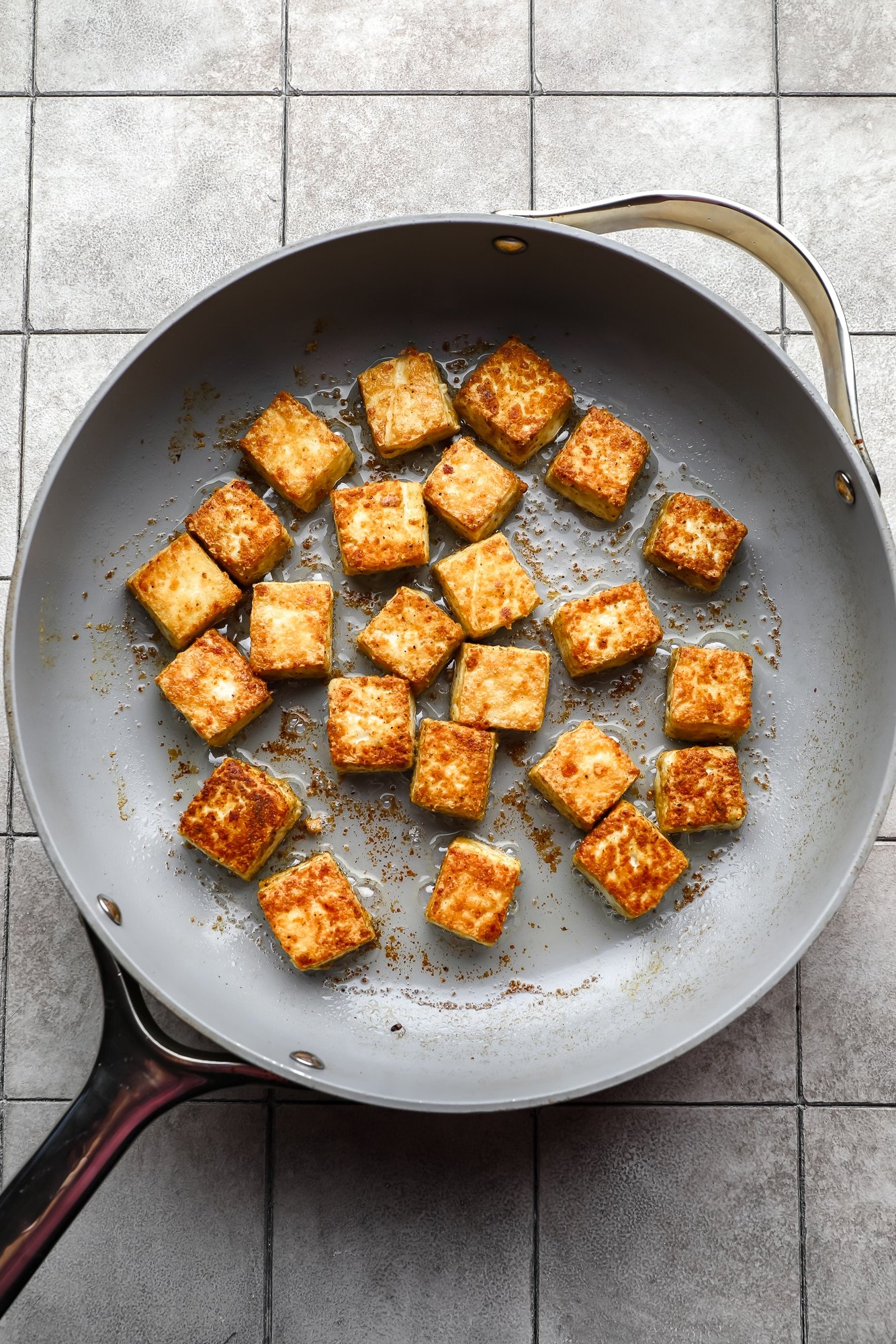 frying seasoned tofu cubes in a large metal skillet.