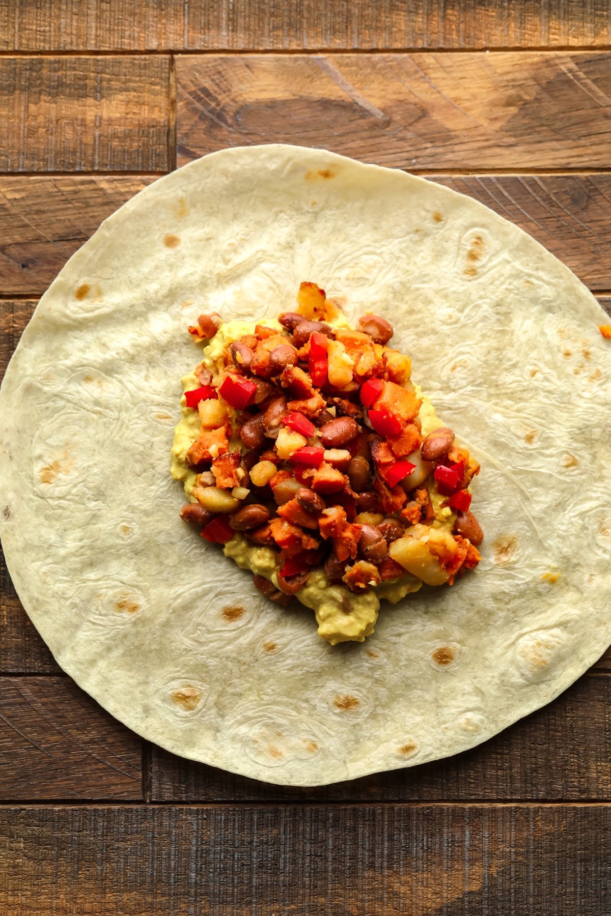 tortilla on wood board with veggie potato beans and eggy mixture