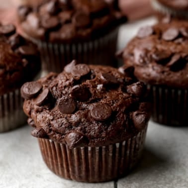 square image of close up of chocolate muffin with chocolate chips on top
