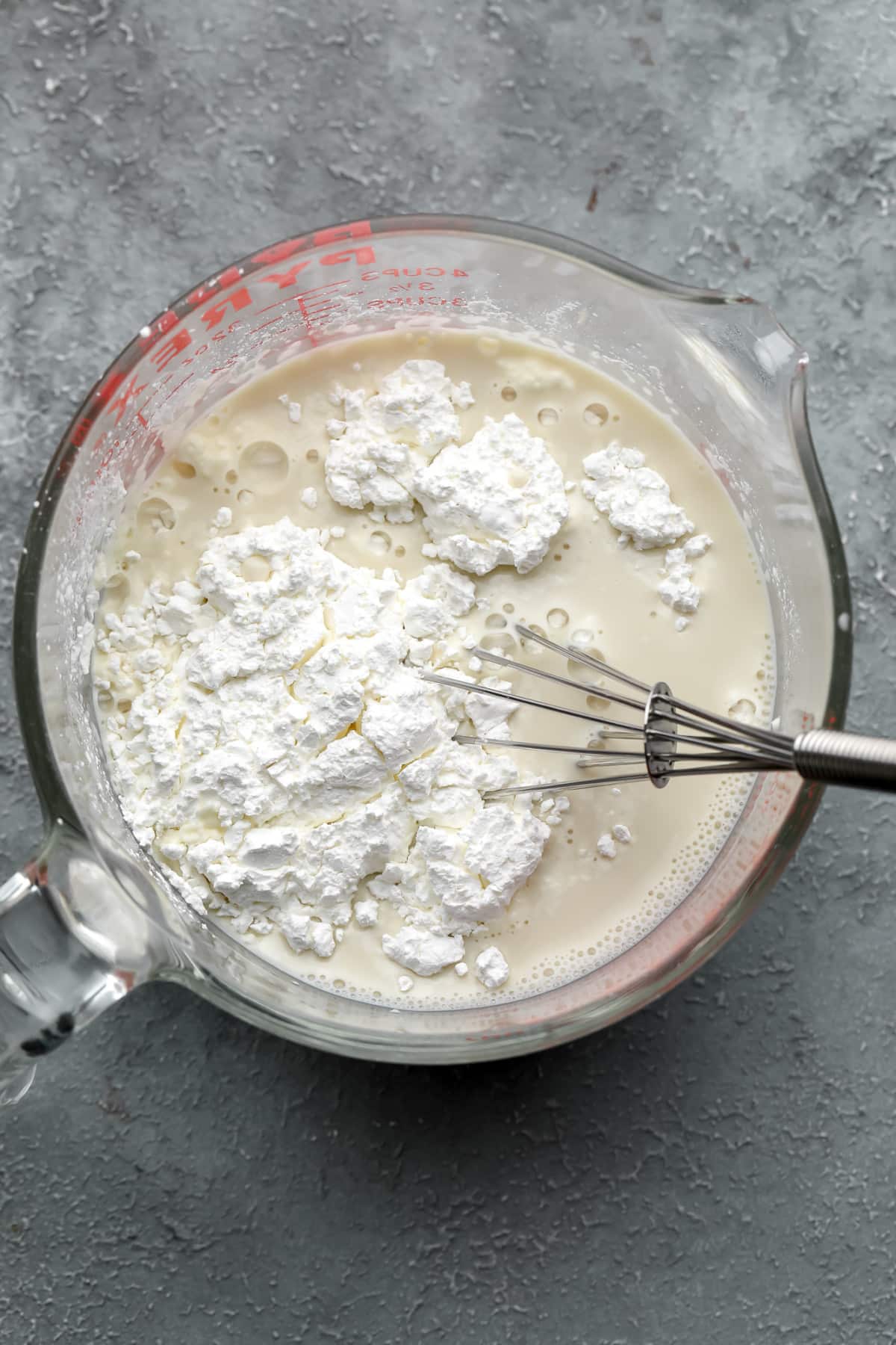 whisking cornstarch into plant milk in a glass measuring cup.