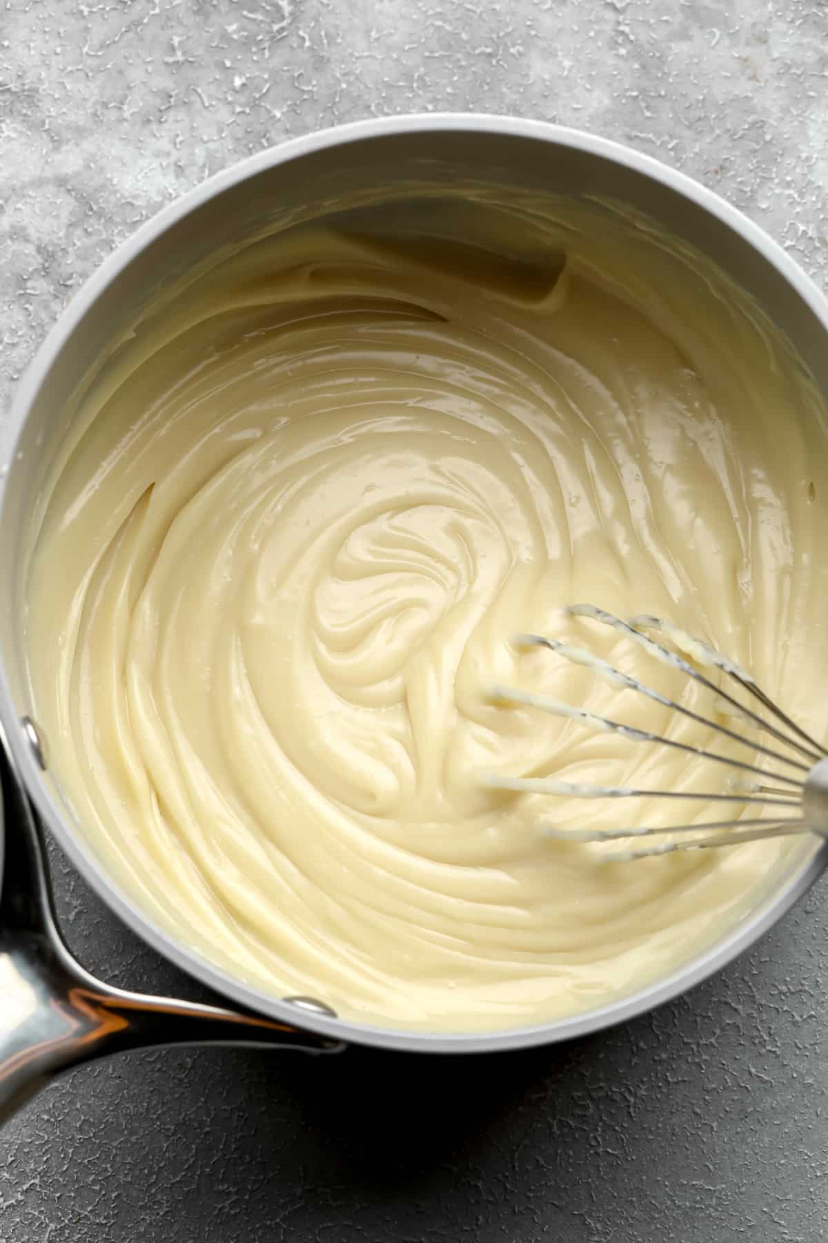 whisking vegan custard in a saucepan.