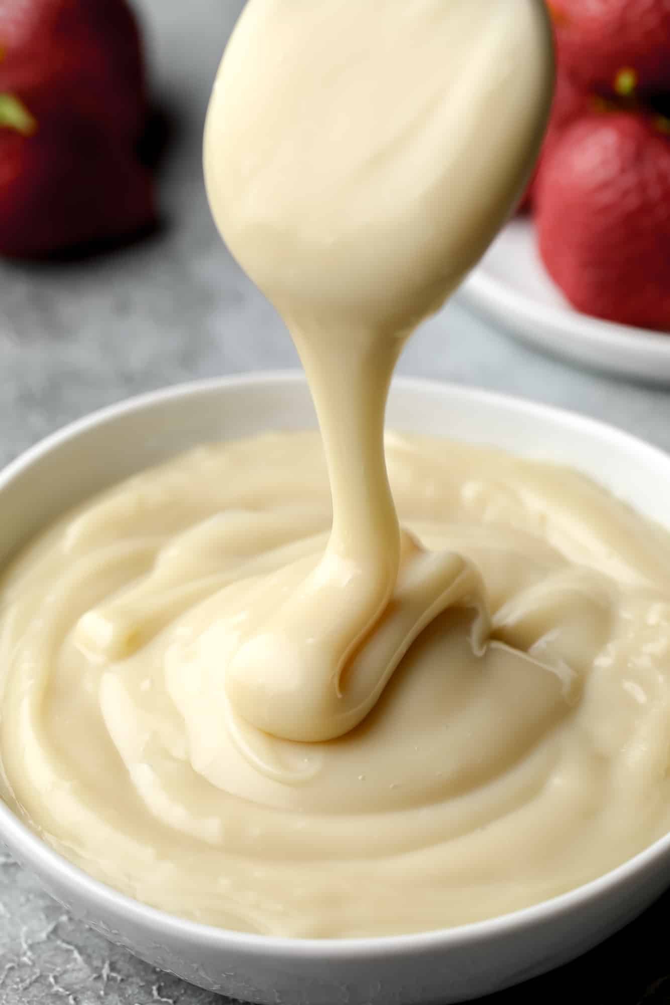 drizzling vegan custard in a white bowl.