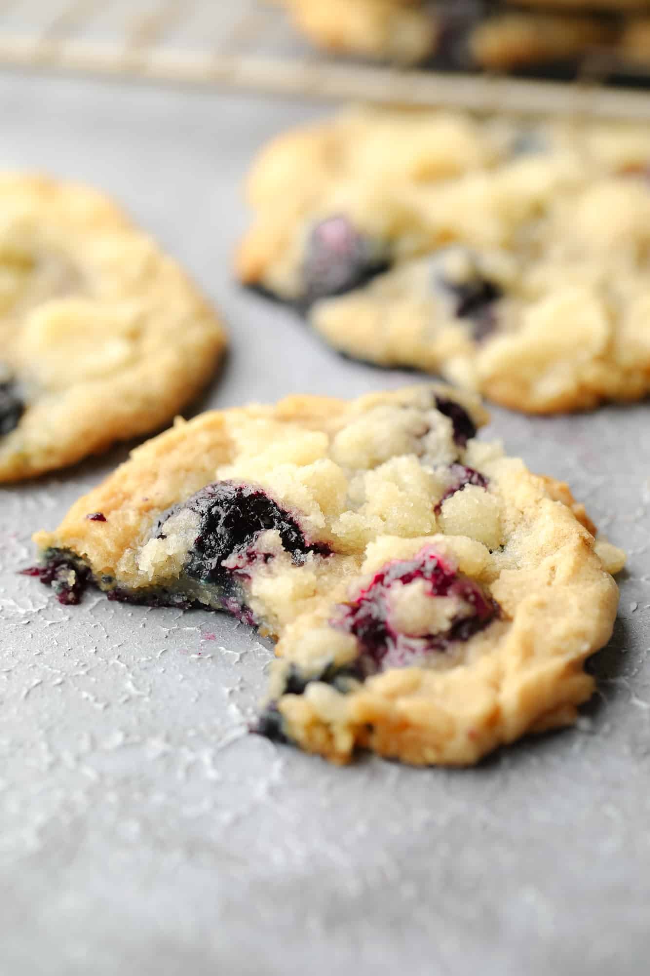 close up on a blueberry cookie with a bite taken out of it.