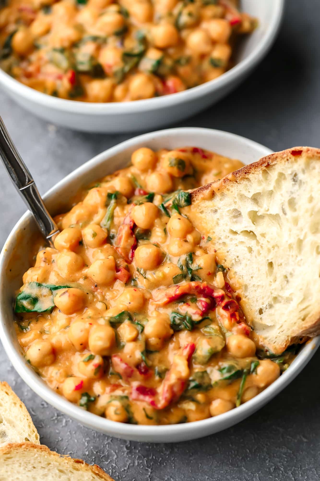 a piece of bread dunked in a bowl of Marry Me Chickpeas.