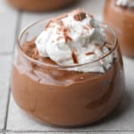 close up on tofu chocolate mousse topped with whipped cream in a glass jar.