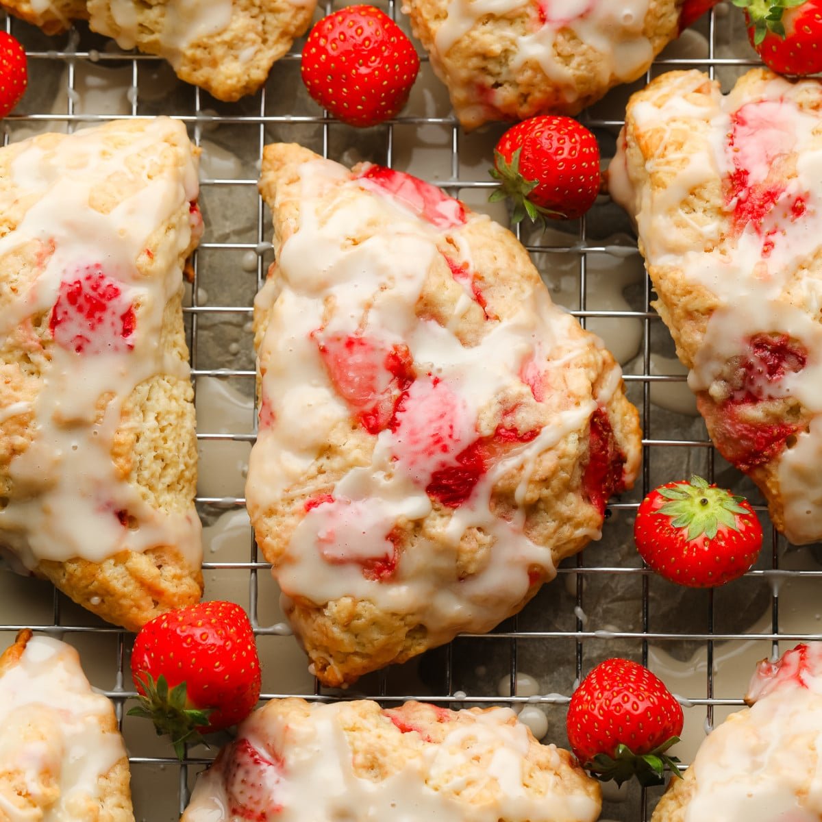 close up on a baked strawberry scone topped with vanilla glaze.