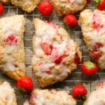 close up on a baked strawberry scone topped with vanilla glaze.