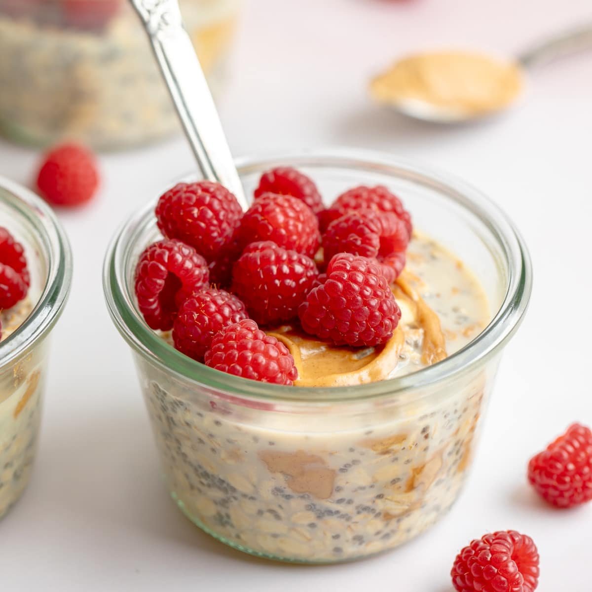 close up on a jar of peanut butter overnight oats topped with fresh raspberries.