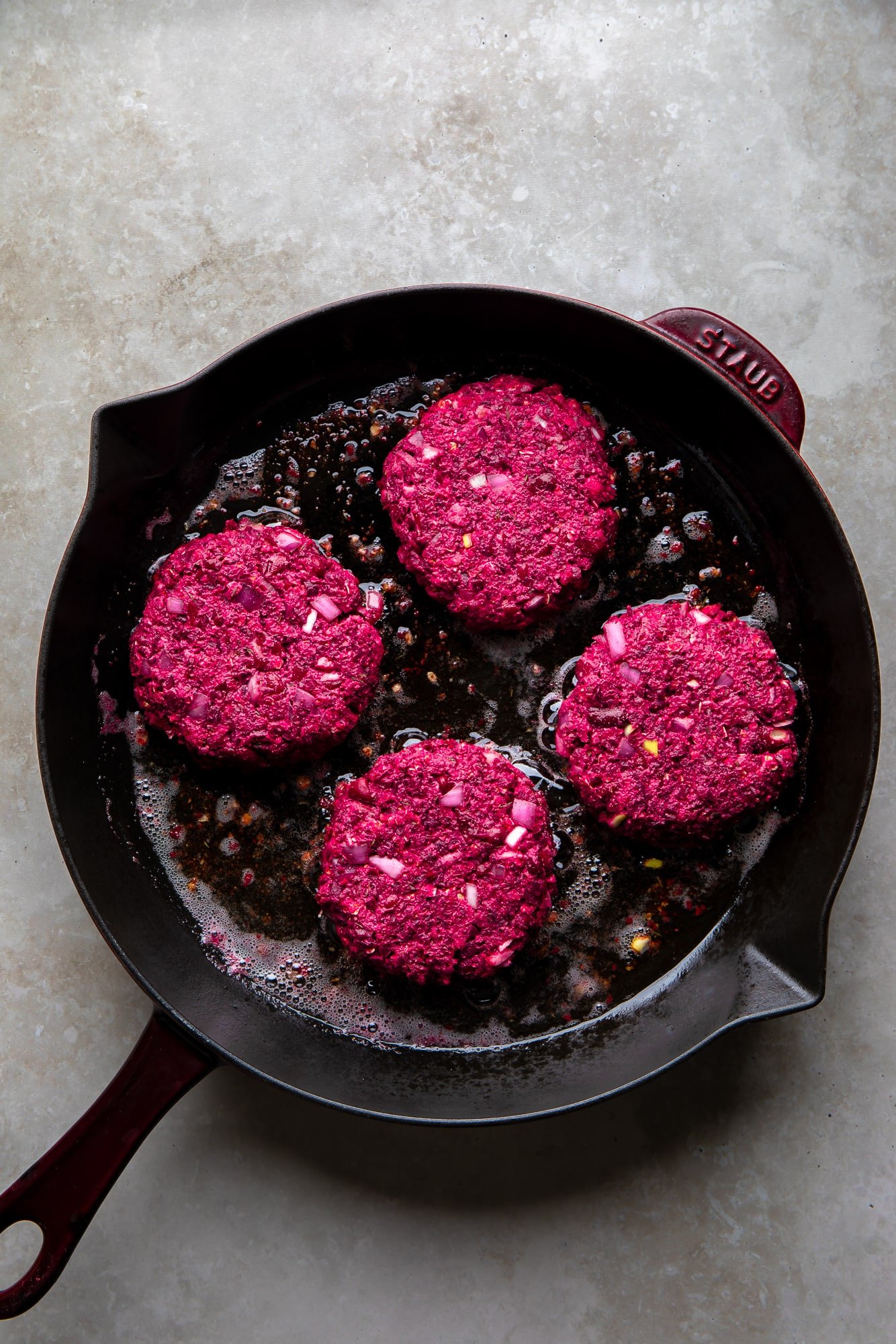 frying 4 kidney beet burgers in a cast iron pan.