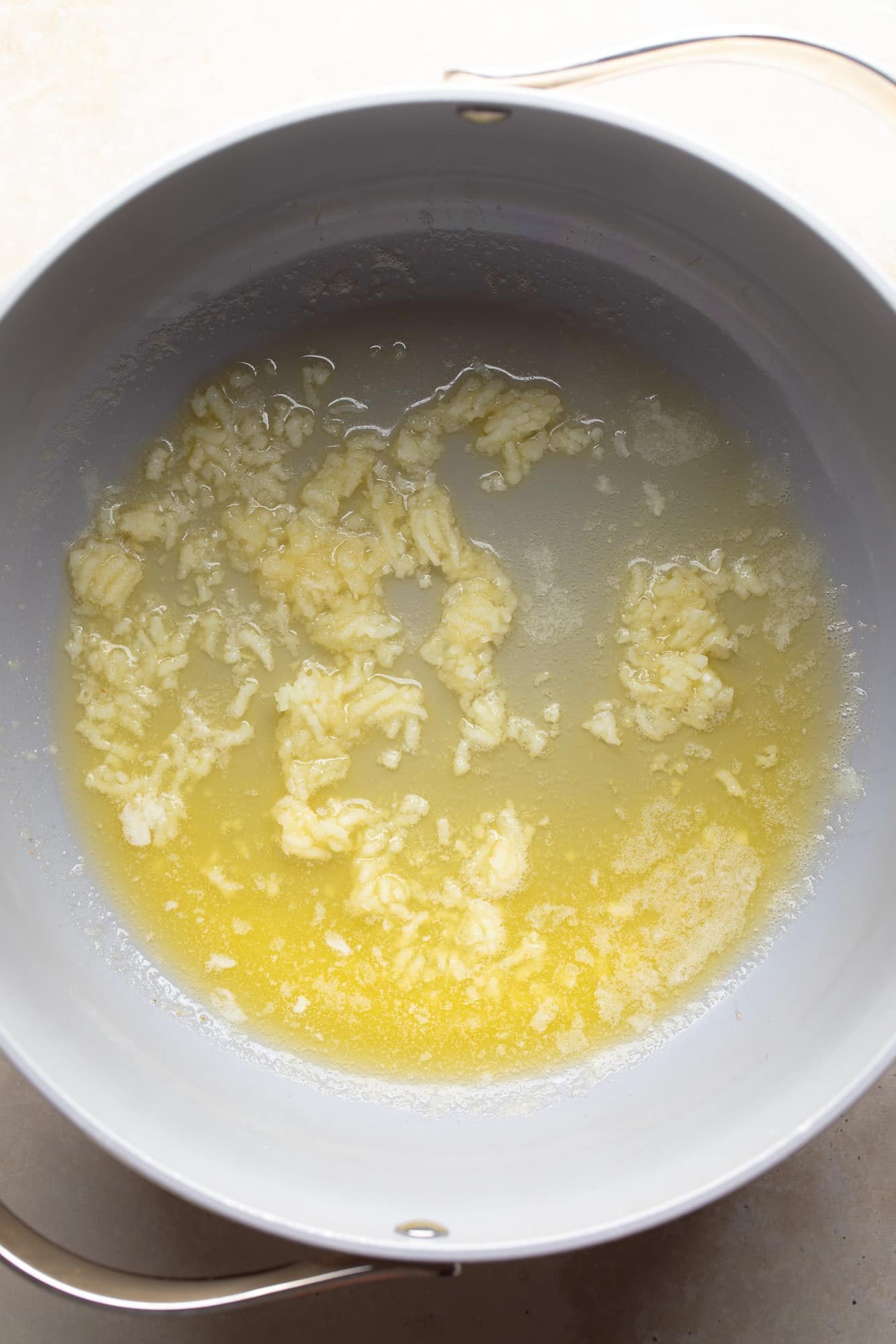 sauteeing garlic in melted butter in a grey skillet.