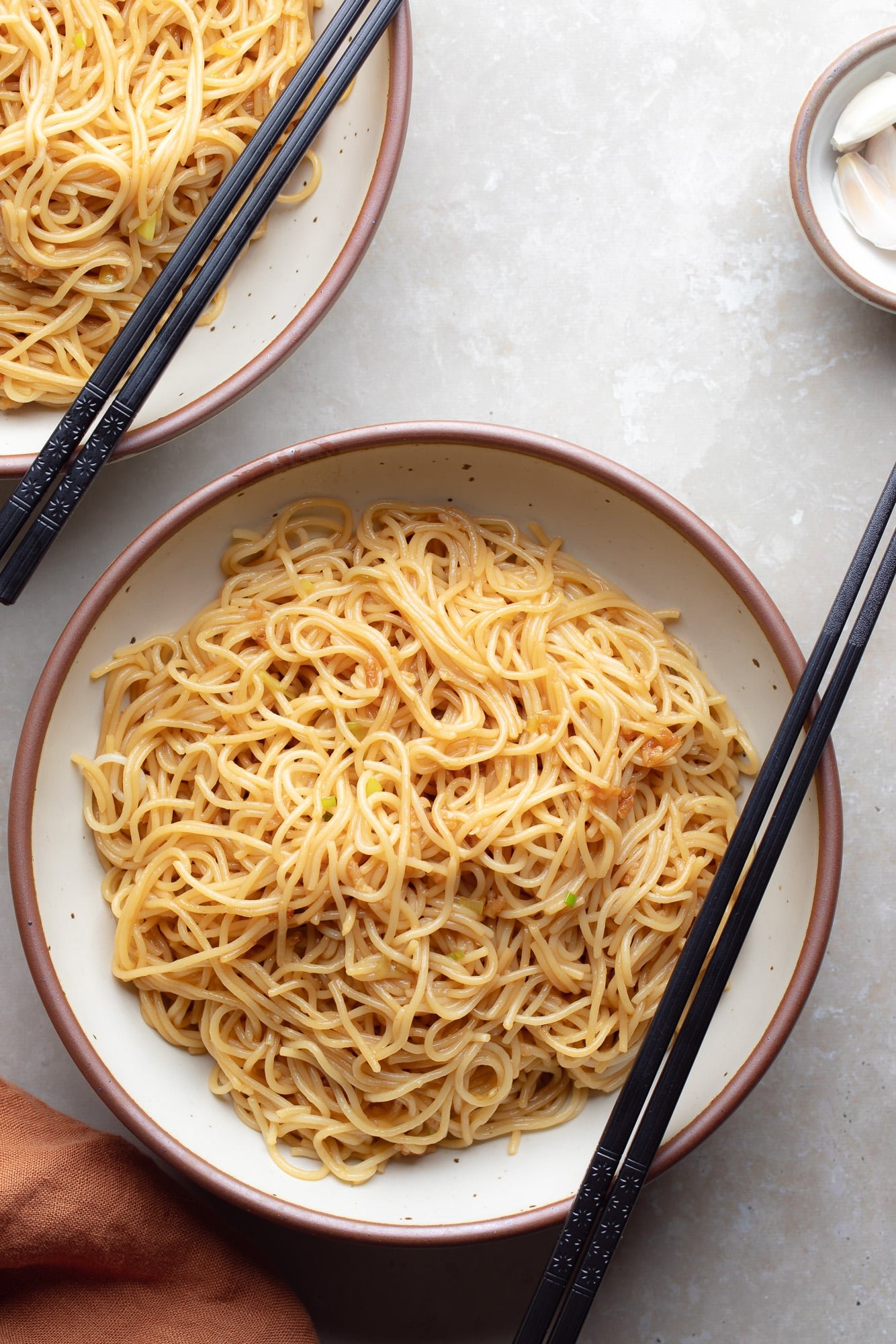 garlic noodles in a white bowl with black chopsticks resting on top.