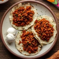 three tortillas topped with vegan chorizo on a plate.