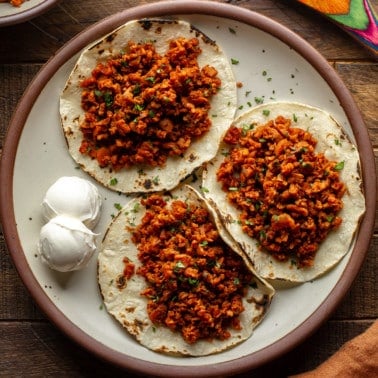 three tortillas topped with vegan chorizo on a plate.