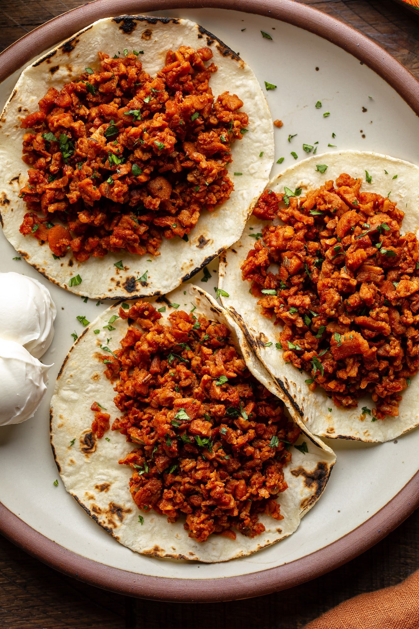 three tortillas topped with vegan chorizo on a plate.