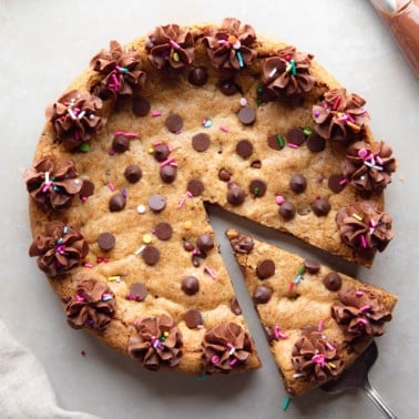 close up on a slice of a vegan cookie cake being lifted away from the whole cake.