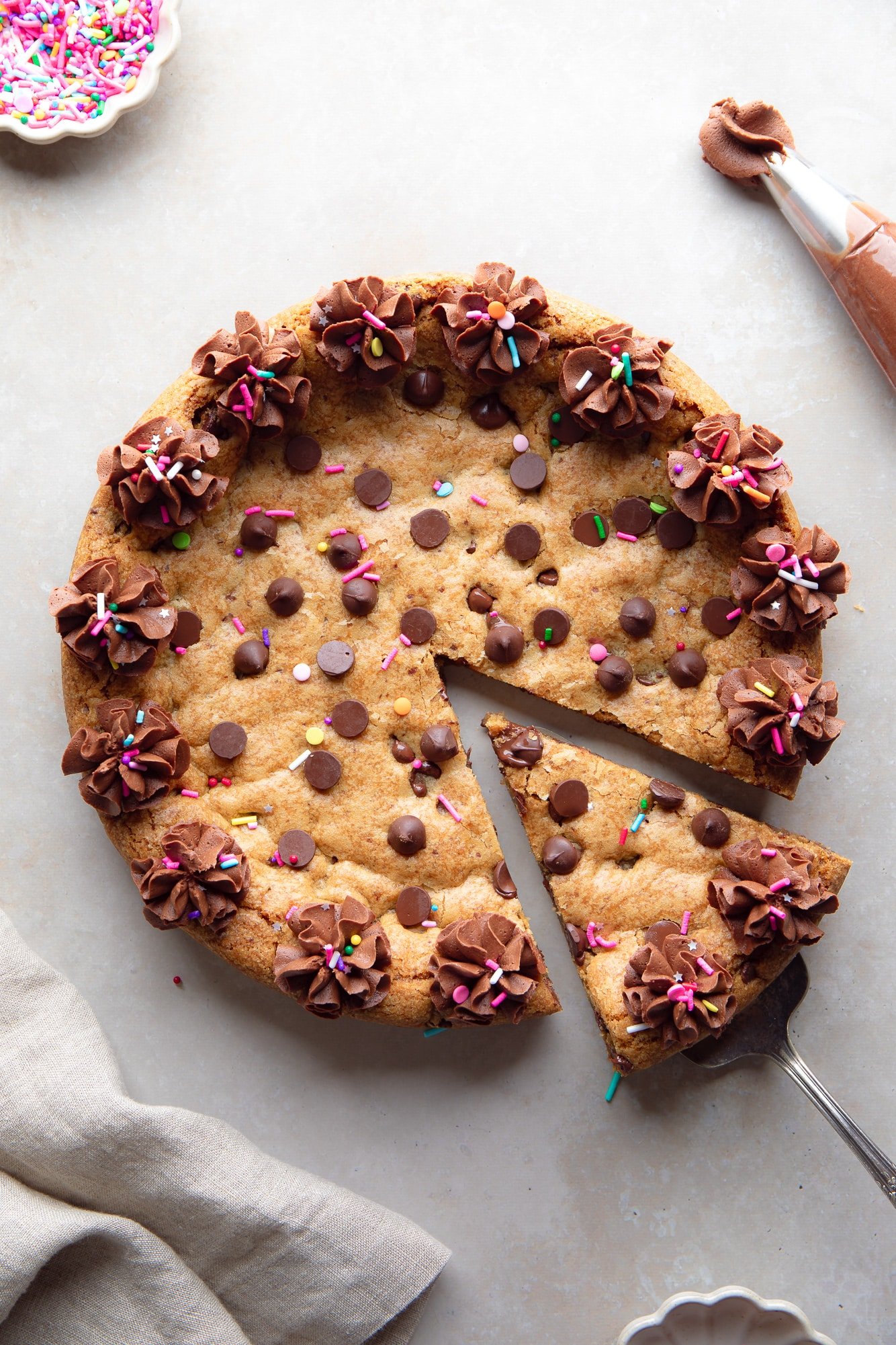 a slice of a vegan cookie cake being lifted away from the whole cake.