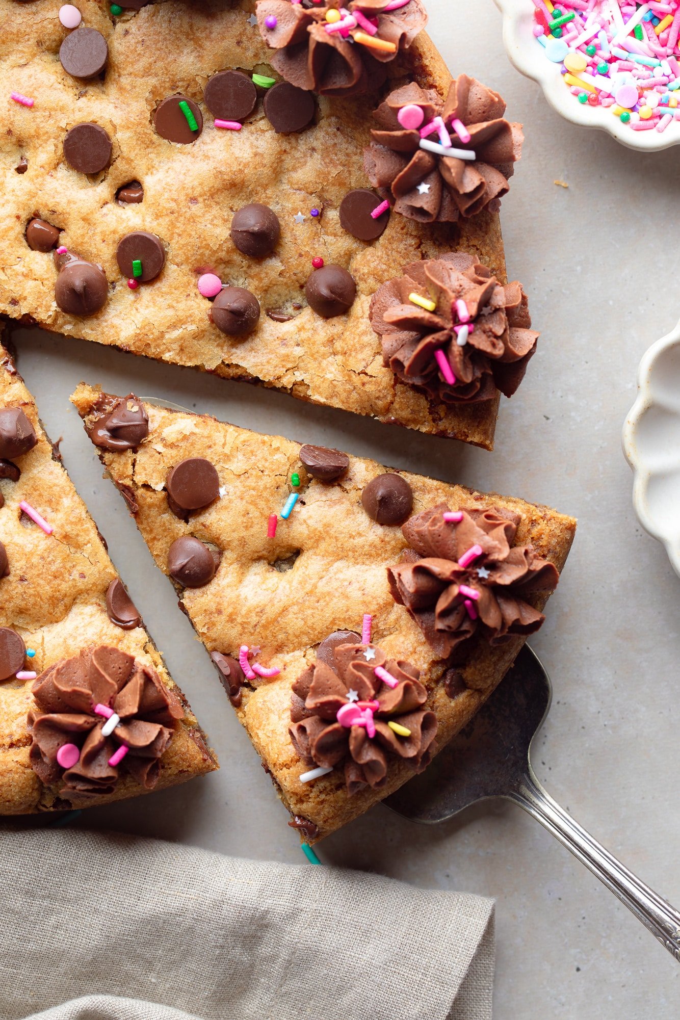close up on a slice of a vegan cookie cake being lifted away from the whole cake.