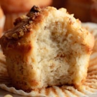 square image of close up of a bite taken out of a golden muffin with nuts