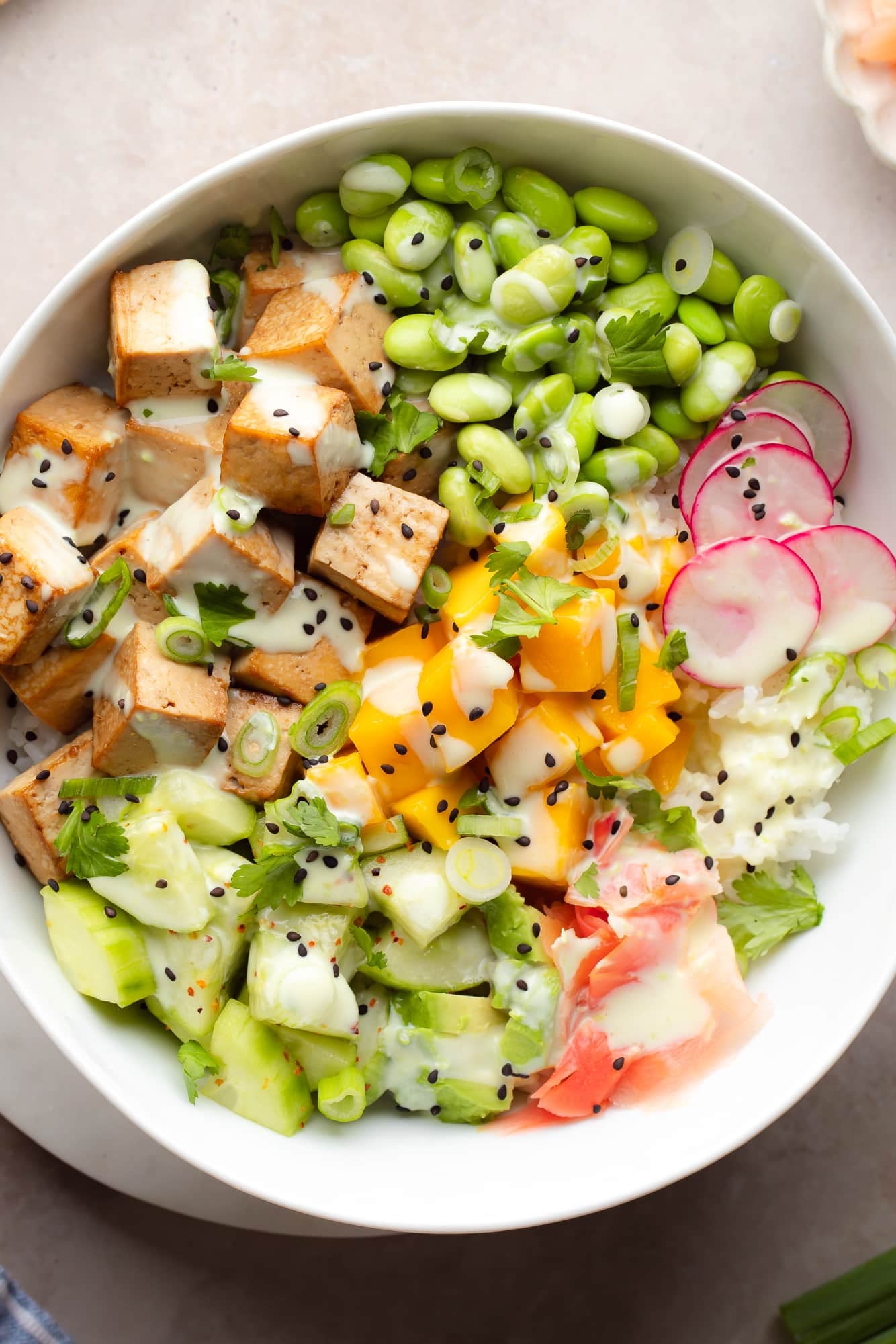 close up on tofu poke bowl with many ingredients on beige background